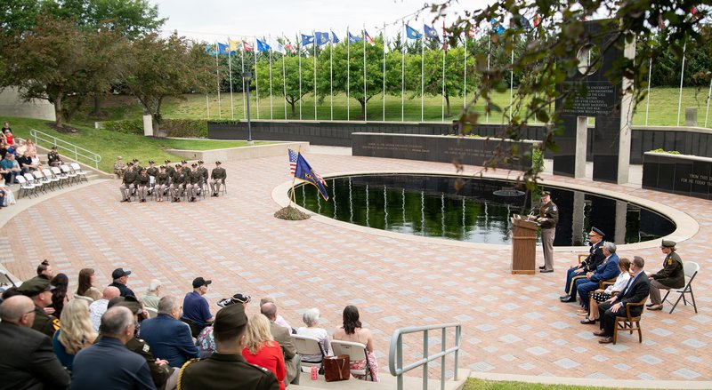 A man at a podium addresses cadets, families and friends.