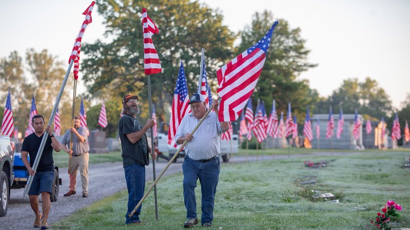 Volunteers place U.S. flags along the lanes in Pittsburg's Highland Park Cemetery.